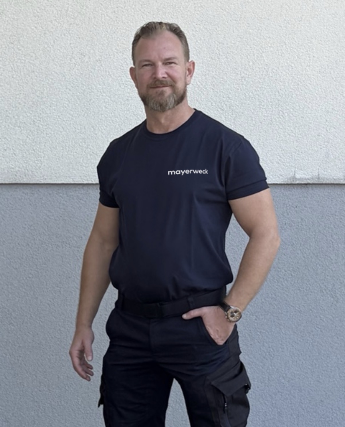 Florian Mayerweck in navyblauer Arbeitskleidung mit mayerweck-Logo